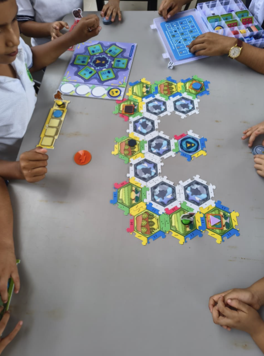 Niños participan en una actividad didáctica con fichas y materiales de colores sobre una mesa.