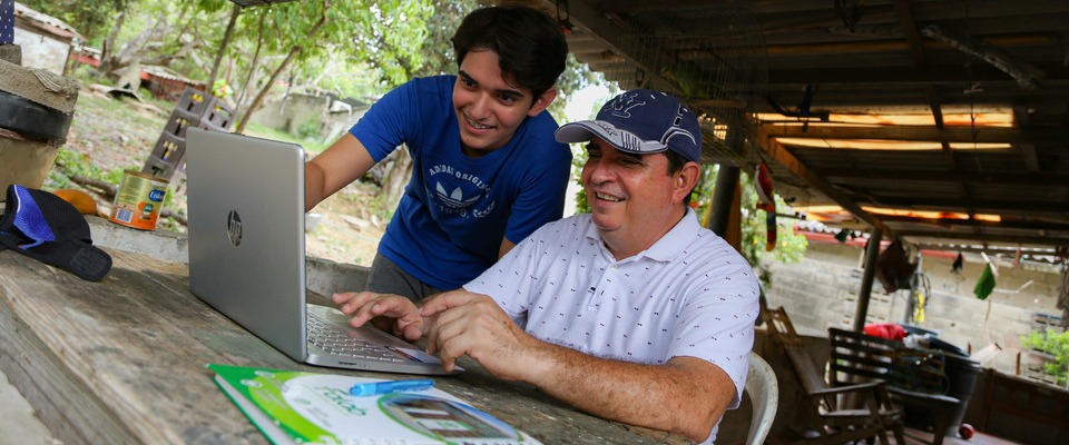 Foto de un joven y un adulto observando un computador