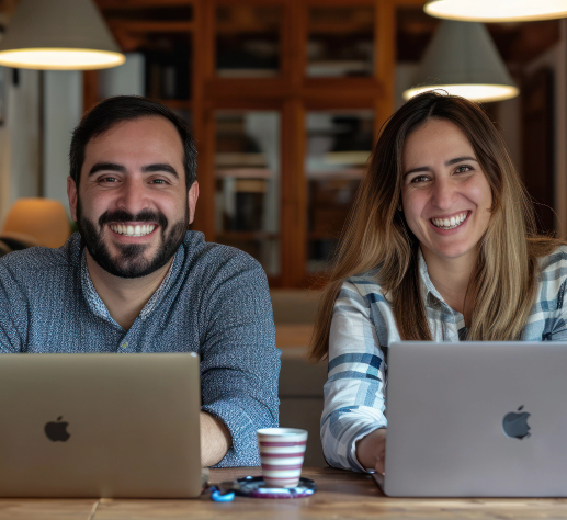Dos personas sonriendo frente a sus computadores