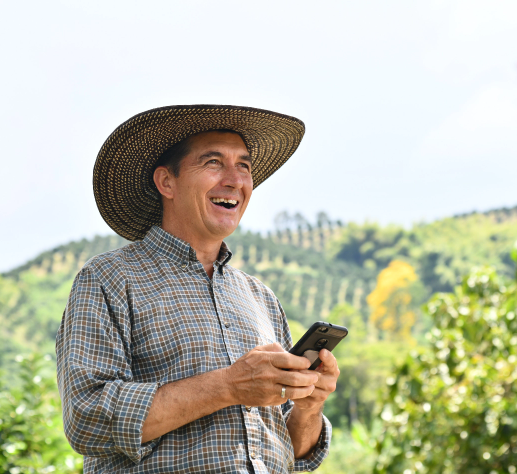 Campesino sonriendo con un celular en la mano