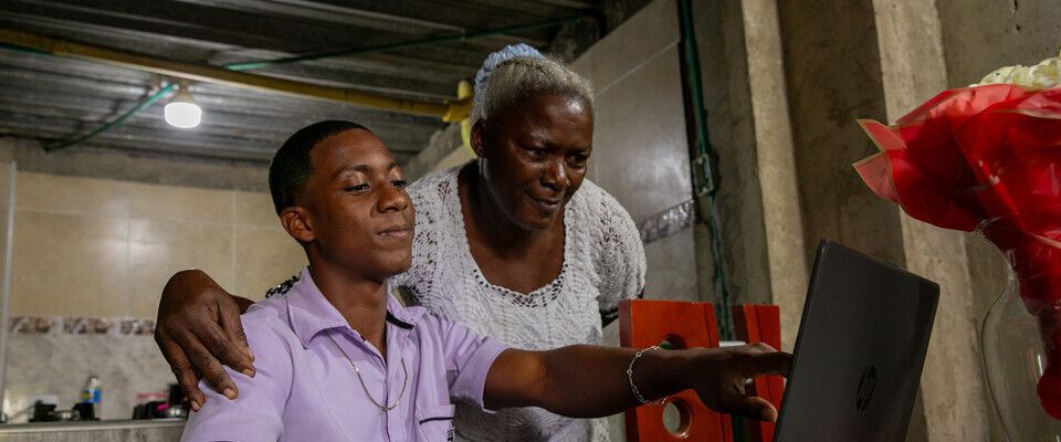Foto de una señora adulto junto a un joven observando un computador Foto de una señora adulto junto a un joven observando un computador
