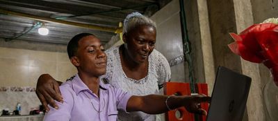 Foto de una señora adulto junto a un joven observando un computador