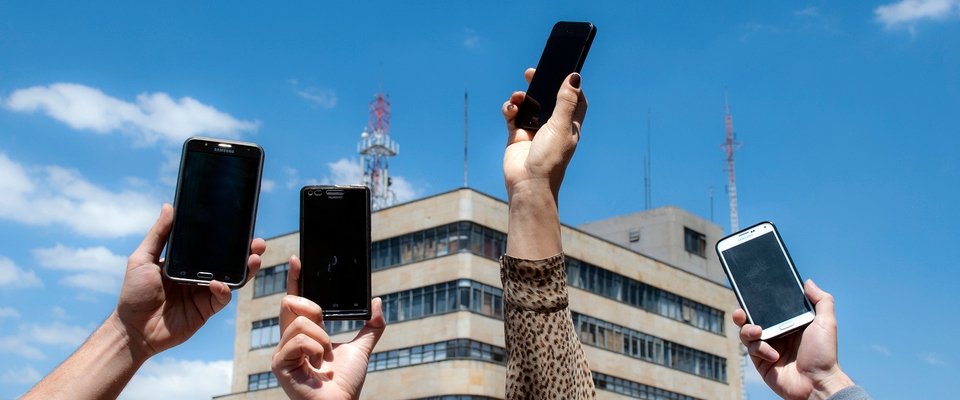 Foto de 4 manos sosteniendo dispositivos moviles