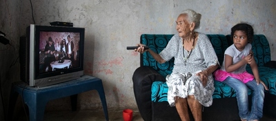 Foto de un adulto mayor junto a una menor de edad viendo televisión Foto de un adulto mayor junto a una menor de edad viendo televisión