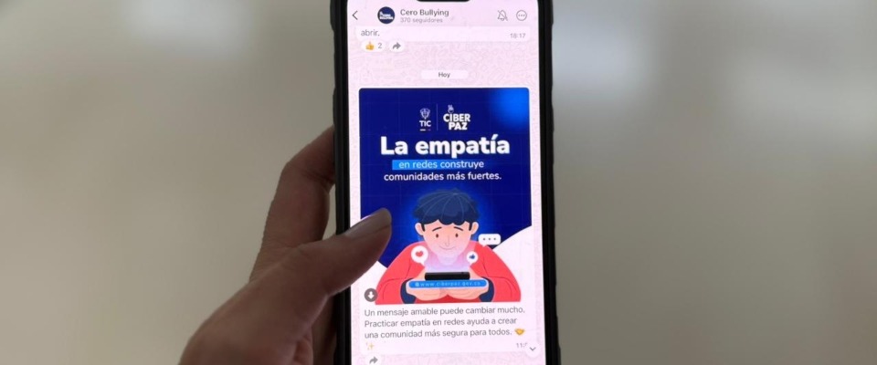 Foto de de un teléfono móvil sostenido por unas manos y navegando un mensaje de CiberPaz