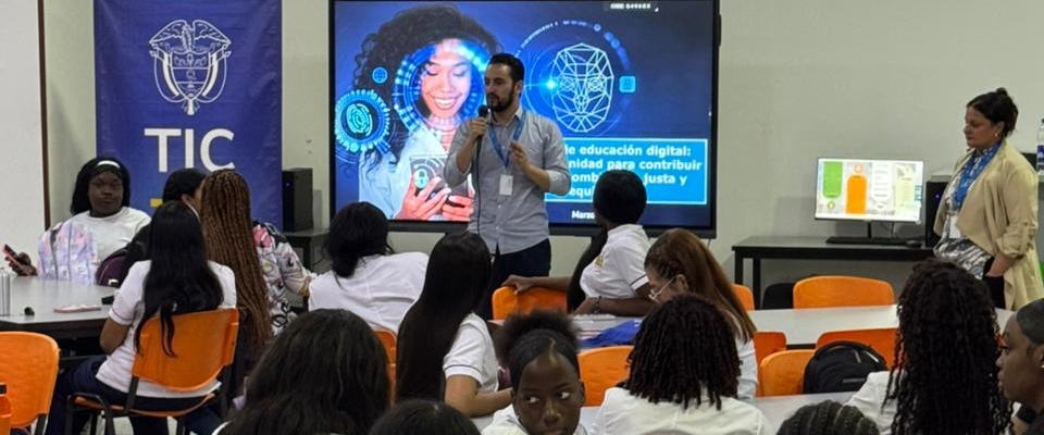 Taller sobre educación digital con estudiantes y facilitadores en aula. Presentación frente a pantalla con contenidos TIC y participación activa del grupo