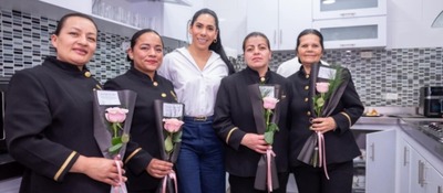 Ministra TIC y colaboradores con uniforme sostienen rosas rosadas, en un gesto de reconocimiento y celebración.