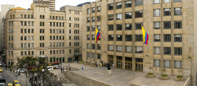 Vista de edificio institucional con banderas de Colombia en la fachada y una plaza al frente, en una zona céntrica de la ciudad