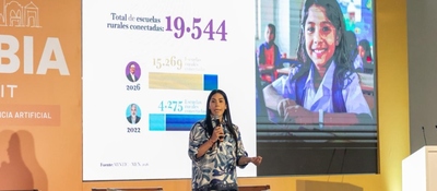 Foto de la Ministra TIC en presnetación durante el evento, al fondo una pantalla con la imagen de una niña