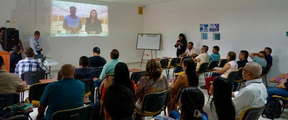 Personas sentadas en aula observan proyección; capacitación sobre implementación de Política de Gobierno Digital en entidades de la Amazonía.