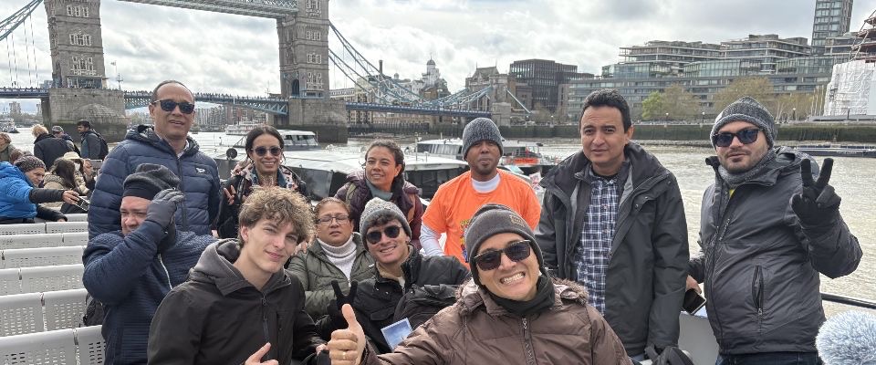 Foto de 11 personas en un recorrido turistico con un puente representativo al fondo