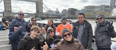 Foto de 11 personas en un recorrido turistico con un puente representativo al fondo