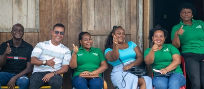 Foto de dos hombres y cuatro mujeres afroamericanos sonriendo y sosteniendo sus manos con el pulgar arriba