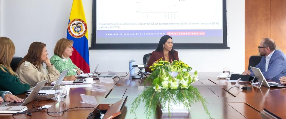 Ministra TIC lidera reunión con operadores en sala de juntas; analizan tarifas e IPC para proteger a usuarios, con bandera de Colombia