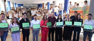 Entrega de computadores en Santander: grupo de funcionarios sostiene portátiles frente a estudiantes con cajas en jornada educativa.
