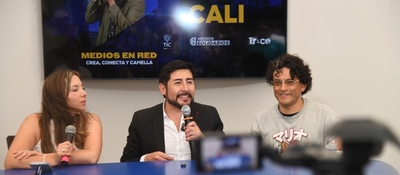 Tres panelistas en mesa hablan con micrófonos; pantalla atrás dice Cali y Medios en Red, sobre impulso a innovación y medios comunitarios.
