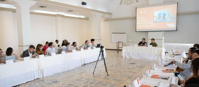 Participantes en mesas en U escuchan panel frente a pantalla sobre AMI; encuentro en Cartagena busca frenar desinformación y promover derechos.