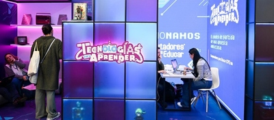 Stand iluminado “Tecnologías para Aprender” en feria; personas exploran y trabajan con laptops. TIC promueve uso responsable e innovación