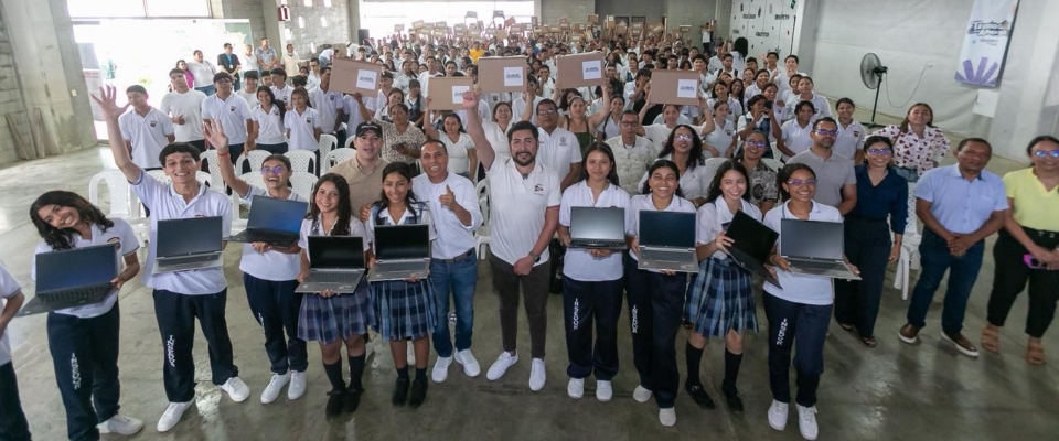 Grupo de estudiantes y docentes sostiene portátiles en un auditorio lleno; texto destaca entregas tecnológicas en Córdoba para fortalecer educación
