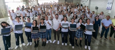 Grupo de estudiantes y docentes sostiene portátiles en un auditorio lleno; texto destaca entregas tecnológicas en Córdoba para fortalecer educación