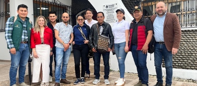 Grupo de diez personas posa frente a edificio institucional; escena vinculada al apoyo del MinTIC a la comunicación indígena.