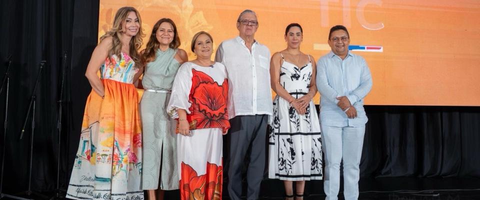 Seis personas posan en escenario frente a pantalla naranja; evento celebra 40 años de Telecaribe como referente cultural del Caribe.