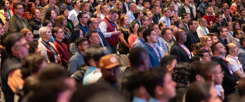 Auditorio lleno de asistentes atentos a una conferencia sobre Bitcoin y economía digital, con público diverso observando el escenario.