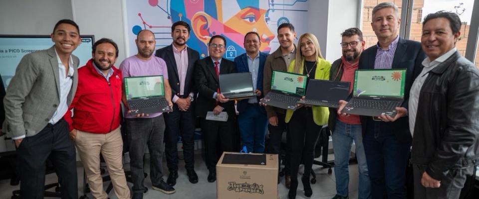Grupo de líderes posa con computadores portátiles en evento sobre innovación territorial y formación STEAM en Bogotá.