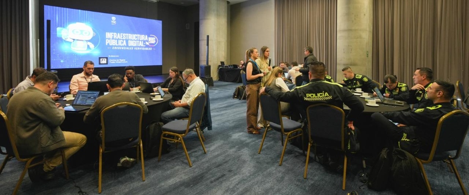 Funcionarios y policías participan en mesas de trabajo sobre Infraestructura Pública Digital en un salón de conferencias