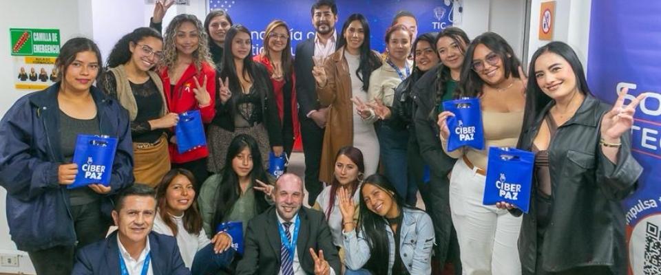 Grupo de mujeres y facilitadores posa en centro tecnológico con materiales de CiberPaz, promoviendo inclusión digital