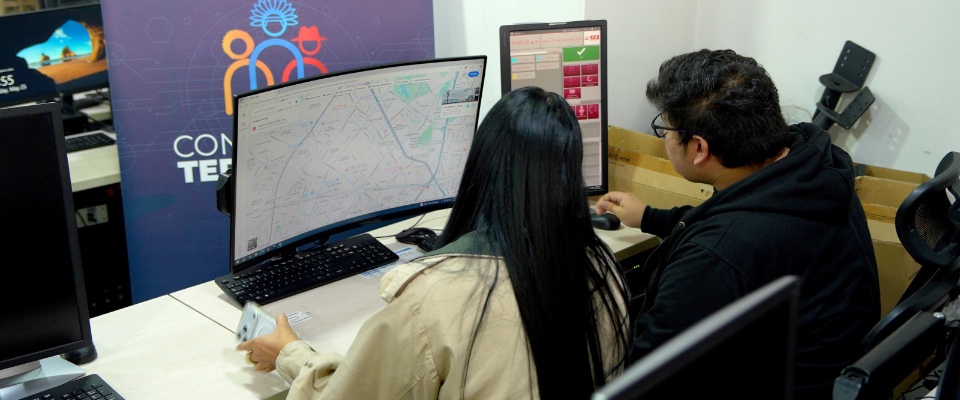Dos personas monitorean mapas y datos en computadores para coordinar atención de emergencias en zonas apartadas.