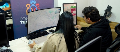 Dos personas monitorean mapas y datos en computadores para coordinar atención de emergencias en zonas apartadas.