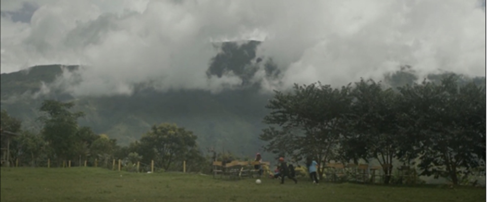 Paisaje rural con montañas cubiertas de niebla y personas en un campo, evocando la diversidad territorial del país