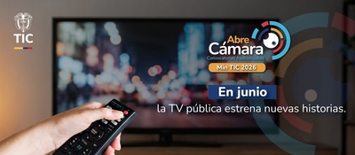 Mano sostiene un control remoto frente a un televisor. Promoción de Abre Cámara anuncia nuevas historias en la TV pública en junio