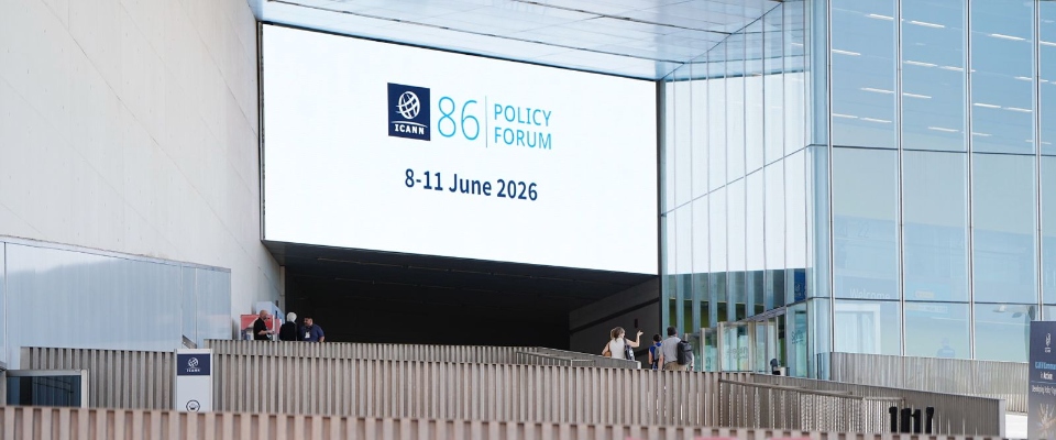 Pantalla gigante anuncia el Foro de Política ICANN 86. Personas recorren el recinto donde se debatirá gobernanza digital