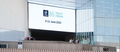 Pantalla gigante anuncia el Foro de Política ICANN 86. Personas recorren el recinto donde se debatirá gobernanza digital