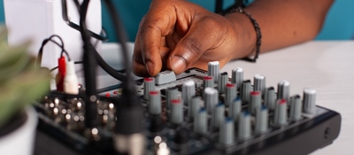 Una persona ajusta una consola de audio con varios controles, asociada a equipos de comunicación y radioafición