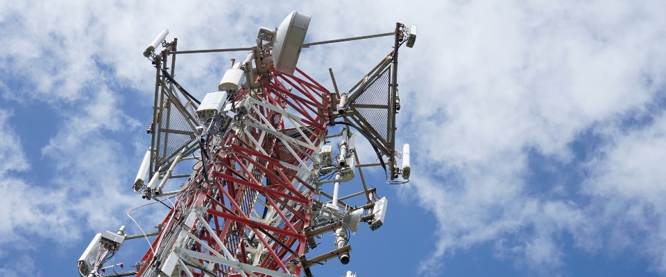 Antena de telecomunicaciones con equipos de transmisión sobre una torre metálica, bajo un cielo parcialmente nublado