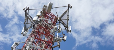 Antena de telecomunicaciones con equipos de transmisión sobre una torre metálica, bajo un cielo parcialmente nublado