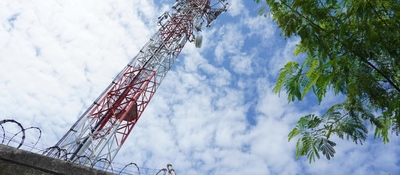 Torre de telecomunicaciones vista desde abajo, con antenas sobre estructura metálica y cielo parcialmente nublado.