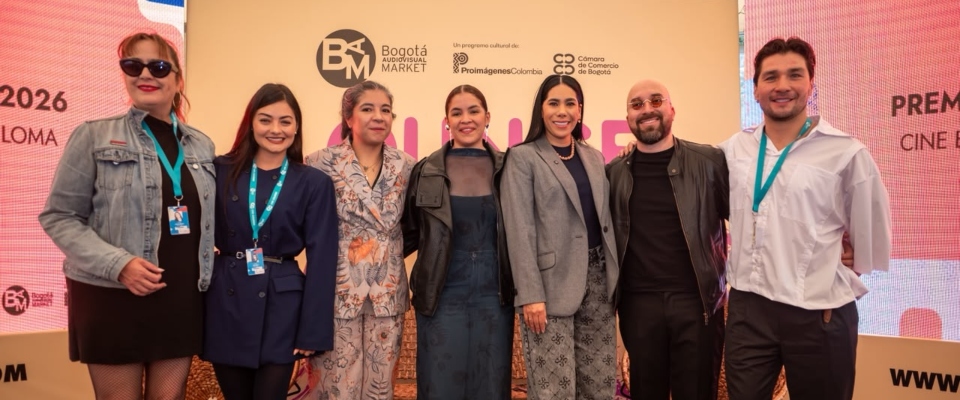 Siete personas posan frente al panel de un evento audiovisual tras el anuncio de las películas nominadas a los Premios Macondo