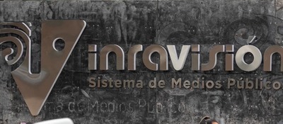 Cartel metálico sobre fondo gris oscuro, con un logotipo y el texto "Sistema de Medios Públicos"