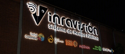 Fachada de ladrillo con letrero iluminado de RTVC Sistema de Medios Públicos y varios logotipos.