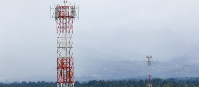 Dos torres metálicas de telecomunicaciones, una grande en primer plano y otra al fondo, sobre un paisaje montañoso.