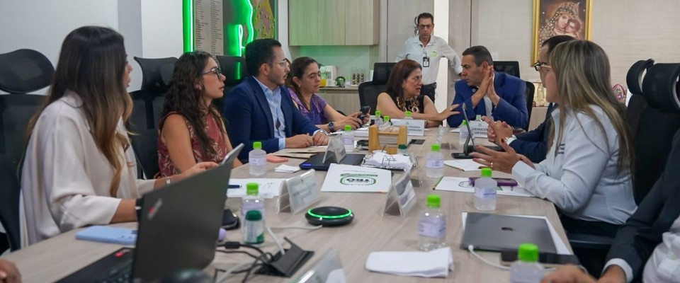 Personas reunidas alrededor de una mesa, conversan y revisan documentos.