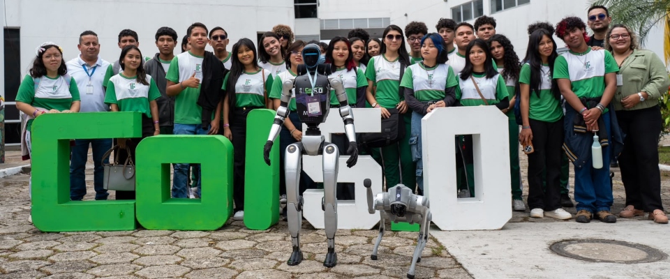 Grupo de personas posa detrás de un robot humanoide y un perro robot, junto a letras grandes verdes y blancas.
