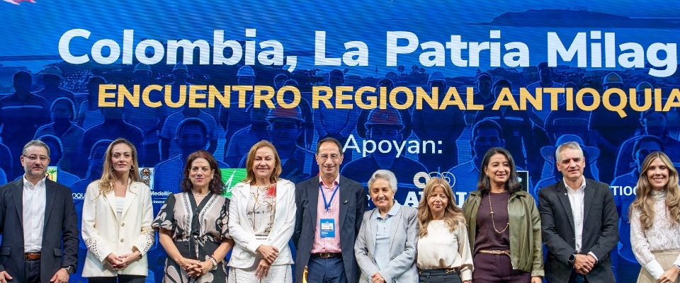 Diez personas posan en fila frente a un fondo azul con el texto «Encuentro Regional Antioquia».
