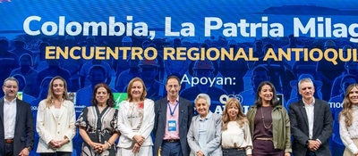 Diez personas posan en fila frente a un fondo azul con el texto «Encuentro Regional Antioquia».